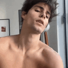 a shirtless young man is sitting in front of a window .