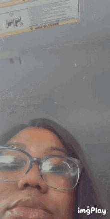 a woman wearing glasses is taking a selfie in front of a sign that says " read this before using "