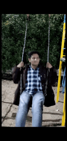 a man in a plaid shirt is sitting on a chain swing