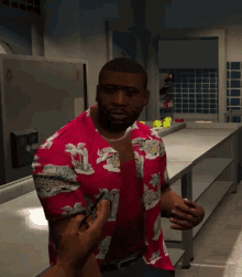 a man in a red shirt with a hawaiian print is standing in a kitchen