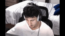 a man wearing headphones is sitting in a chair in front of a computer screen .