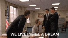 a group of people standing around a desk with the words we live inside a dream on the bottom