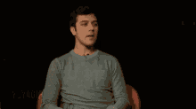 a man in a grey sweater is sitting in a red chair .