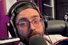 a man wearing glasses and headphones is talking into a microphone .
