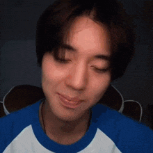 a close up of a man 's face with his eyes closed and a blue shirt on .