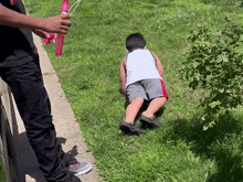 a young boy is being pulled by a person on a leash while a man holds a red balloon .