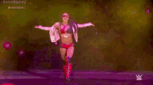 a woman is dancing on a stage with her arms outstretched in a wrestling match .