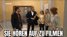 a group of people are standing next to each other in a hallway and talking to each other .