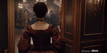 a woman in a red dress is standing in a room with a group of people .