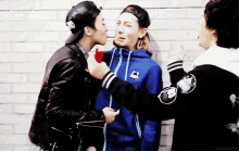 a man in a blue jacket kisses another man on the cheek .