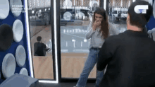 a man and a woman are standing in front of a glass door