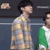 a man wearing glasses and a plaid shirt is standing next to another man in a green sweater .