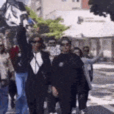 a group of people are walking down a street while holding flags in the air .