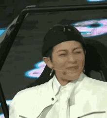 a woman wearing a black hat and a white jacket is sitting in a car with her eyes closed