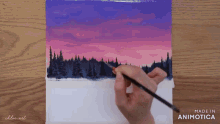a person is painting a sunset over a forest with a brush