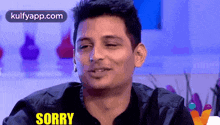 a man in a black jacket is making a funny face and saying sorry .