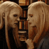 a man and a woman are looking at each other in front of a bookshelf in a library .