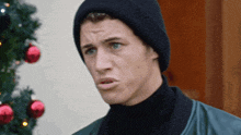 a young man wearing a black hat and turtleneck is making a funny face .