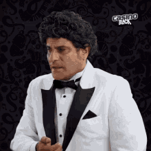 a man in a tuxedo is standing in front of a casino black sign
