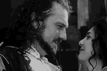 a man with a beard and a woman with long hair are looking at each other in a black and white photo .
