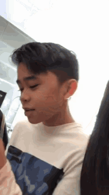 a young boy wearing a white shirt and a blue shirt is looking at the camera .