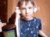 a boy wearing headphones and a blue shirt is standing in front of a microphone