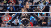 a woman is standing in a wrestling ring with a crowd watching ..