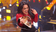 a woman in a red shirt is holding a championship belt