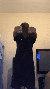a man in a black shirt and hat stands in front of a television