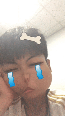 a young boy with a bone on his head and tears coming out of his eyes