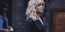 a woman with blonde hair and bangs is wearing a black suit and looking at the camera .