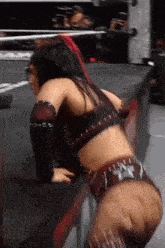 a woman is kneeling down in a wrestling ring while wearing a crop top .