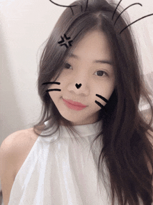 a woman wearing a white top has a cat face drawn on her face