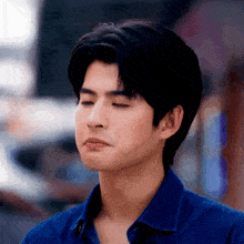 a man in a blue shirt is making a funny face .