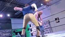 two men are wrestling in a ring with a sign on the wall that says " the day "
