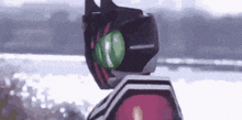 a robot is standing in front of a body of water with a green ball in its head .