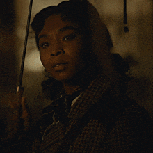 a woman in a plaid coat holds an umbrella in her hand