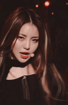 a woman with long hair is wearing a choker and looking at the camera