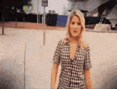 a woman in a plaid shirt is standing in front of a building with a sign that says ' rs ' on it