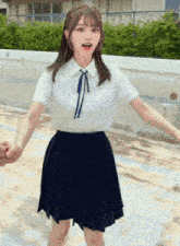 a girl in a white shirt and blue skirt is holding a man 's hand