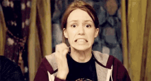 a woman in a hoodie is making a funny face while holding a piece of paper in her mouth .