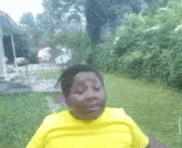 a young girl in a yellow shirt is standing in the grass