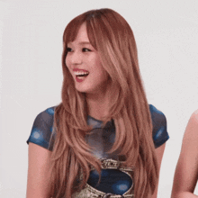 a woman with long blonde hair is smiling and wearing a blue top