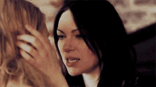 a woman is touching another woman 's face while sitting next to each other .