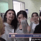 a group of women are standing in a room with a sign that says " can you see me "
