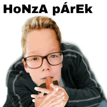 a boy with glasses is holding a hot dog with the words honza parek behind him