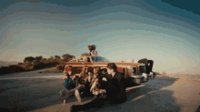 a group of people are sitting in front of a red car