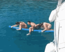 three people are sitting on a blue raft in the ocean