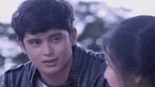 a young man in a leather jacket is looking at a woman .