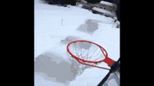 a person is playing basketball in the snow with a red rim